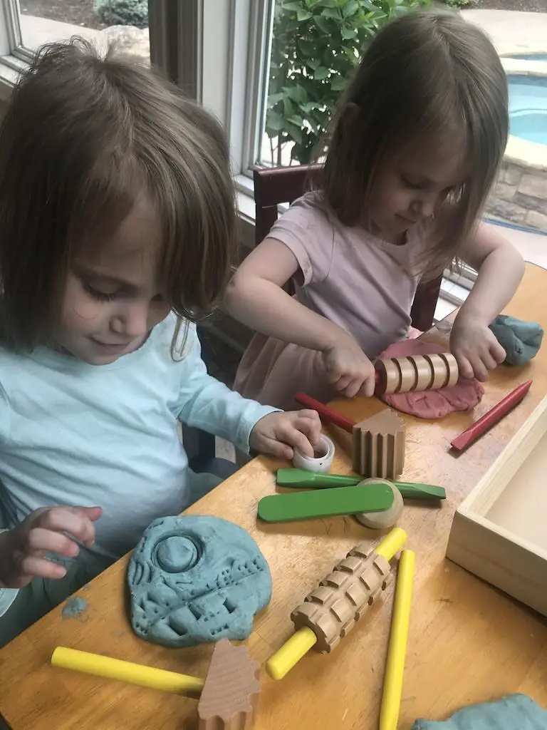 Toddlers playing with play dough and Melissa and Doug tools
